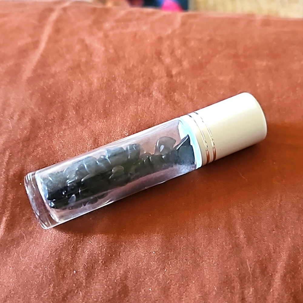 Empty glass roll on bottle with Black Obsidian chips inside